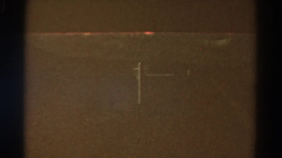 A faint roadside pole and a viewfinder-like crosshair are visible in a low-exposure 1967 Colorado 8mm travel frame.