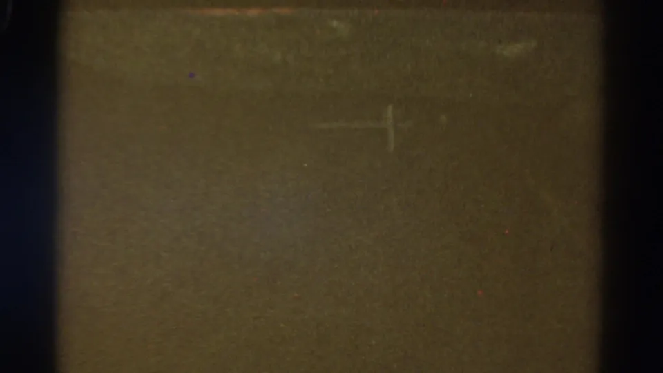 A faint crosshair-like mark sits over a dim roadside view in this final 1967 Colorado 8mm frame from a moving vehicle.