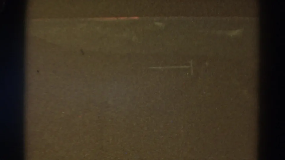 Obscured 1967 Colorado 8mm frame showing a central dark divider, brown-black exposure, fine grain, dust, and light scratch marks.