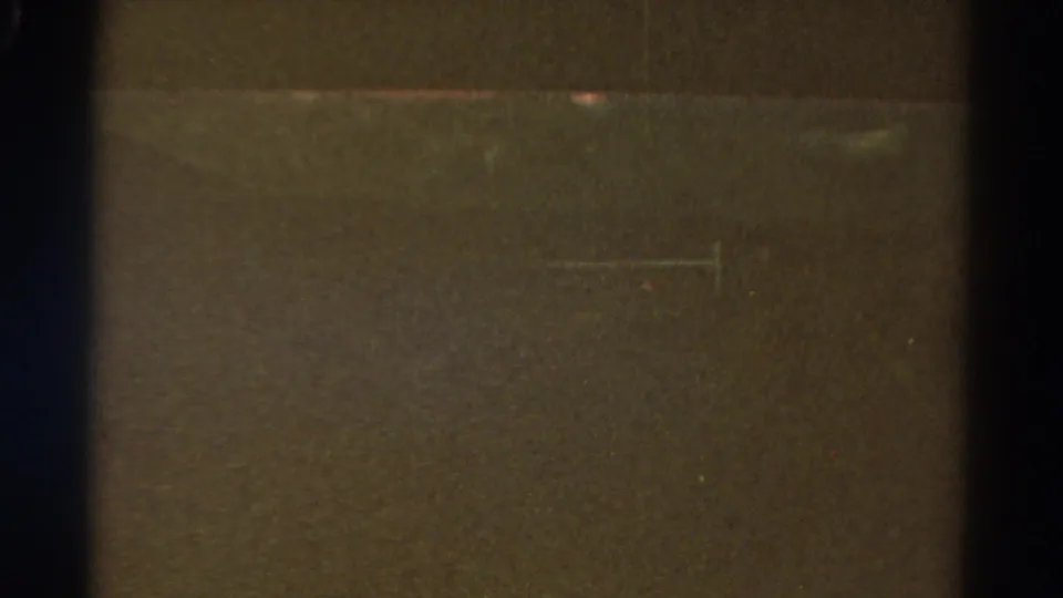 Underexposed 1967 Colorado 8mm frame with a horizontal tonal band, visible film edge, dust, grain, and scratch marks.