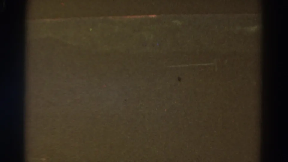 Dark 1967 Colorado 8mm frame with a vertical divider, brown-black underexposure, dust spots, grain, and faint horizontal scratches.