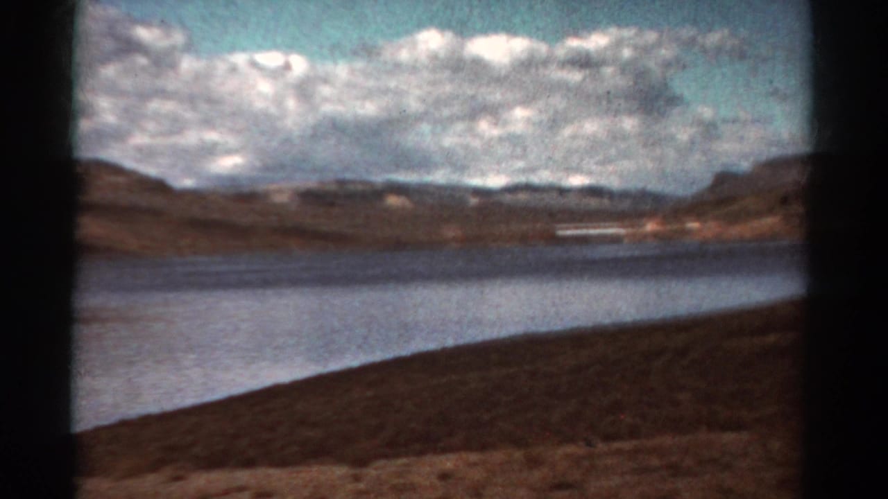 Lake bordered by dry hills under a cloudy sky, with dark 8mm frame edges.