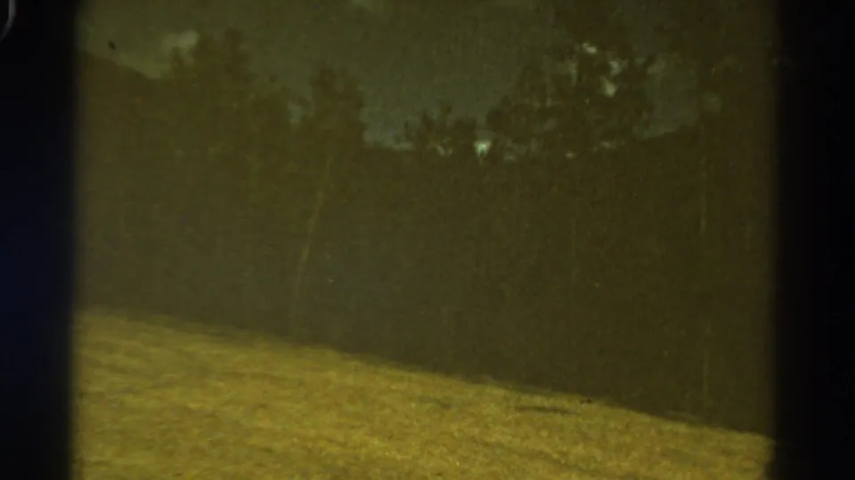 1967 Colorado 8mm frame showing a soft, moving view of grassy land, trees, and cloudy sky from a vehicle.
