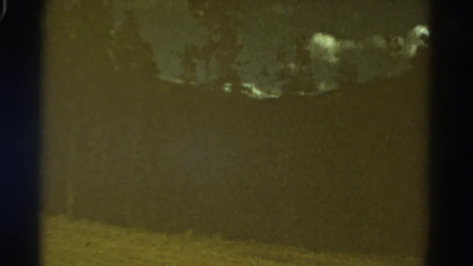 1967 Colorado 8mm frame with dark trees, cloudy sky, and a softly exposed mountain slope.