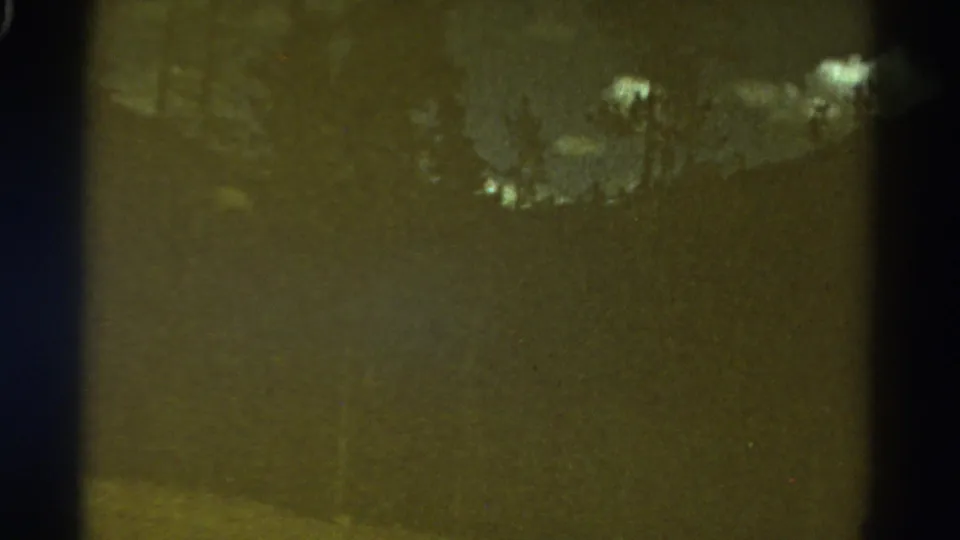 Soft 8mm view of a Colorado mountain ridge with clouds and faint tree shapes in dark exposure.