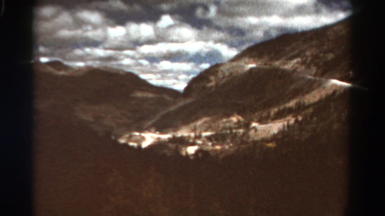 Mountain ridges and bright clouds seen through a dark 8mm frame edge.