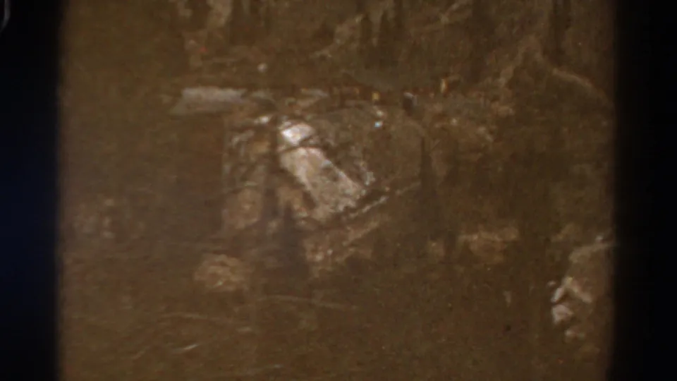 1967 Colorado 8mm frame showing a shadowed valley, hillside contours, and muted storm light through aged color film.