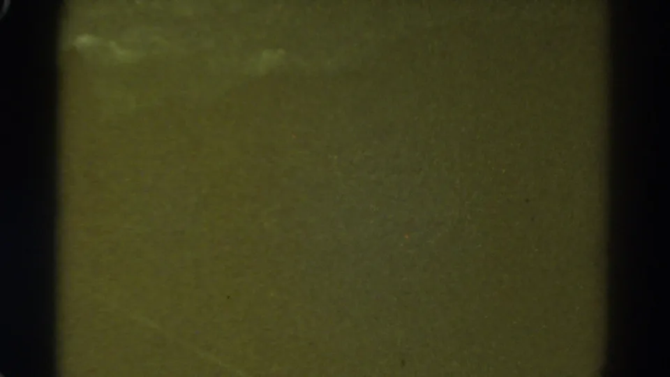 Green-tinted 8mm leader frame with visible grain, dark borders, and no clearly identifiable people or objects.