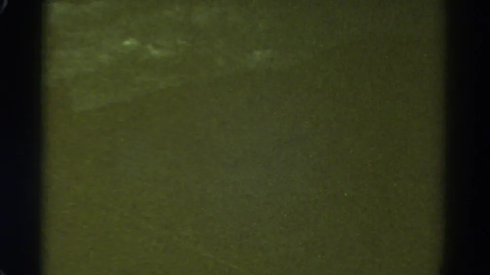1967 Colorado 8mm frame showing a soft green field, dark gate-edge borders, and faint pale cloudlike marks near the top.