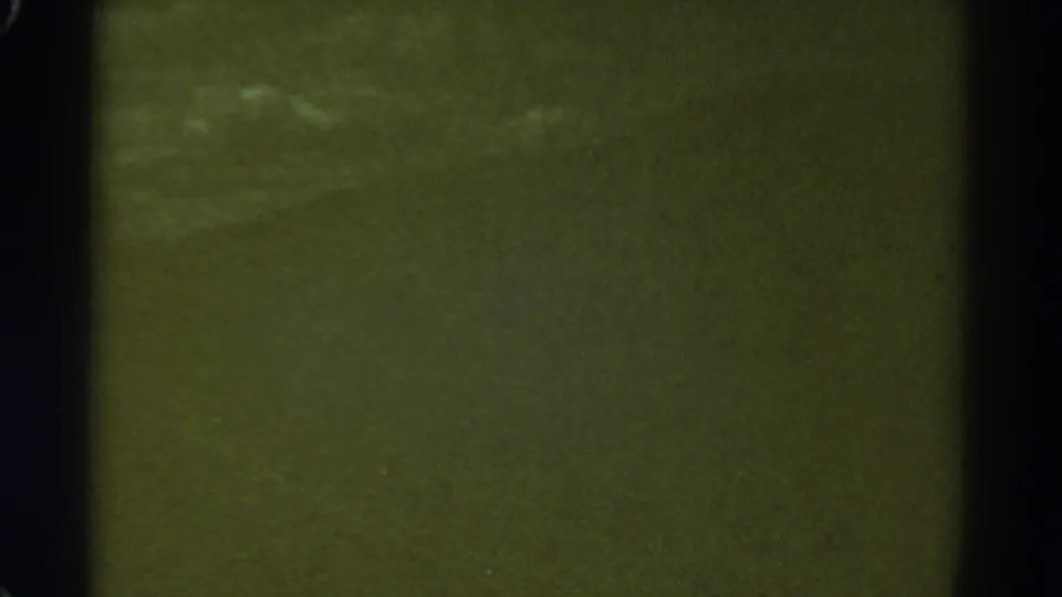 1967 Colorado 8mm frame with a green-tinted blur, dark film border, visible dust, and faint bright smears near the left side.