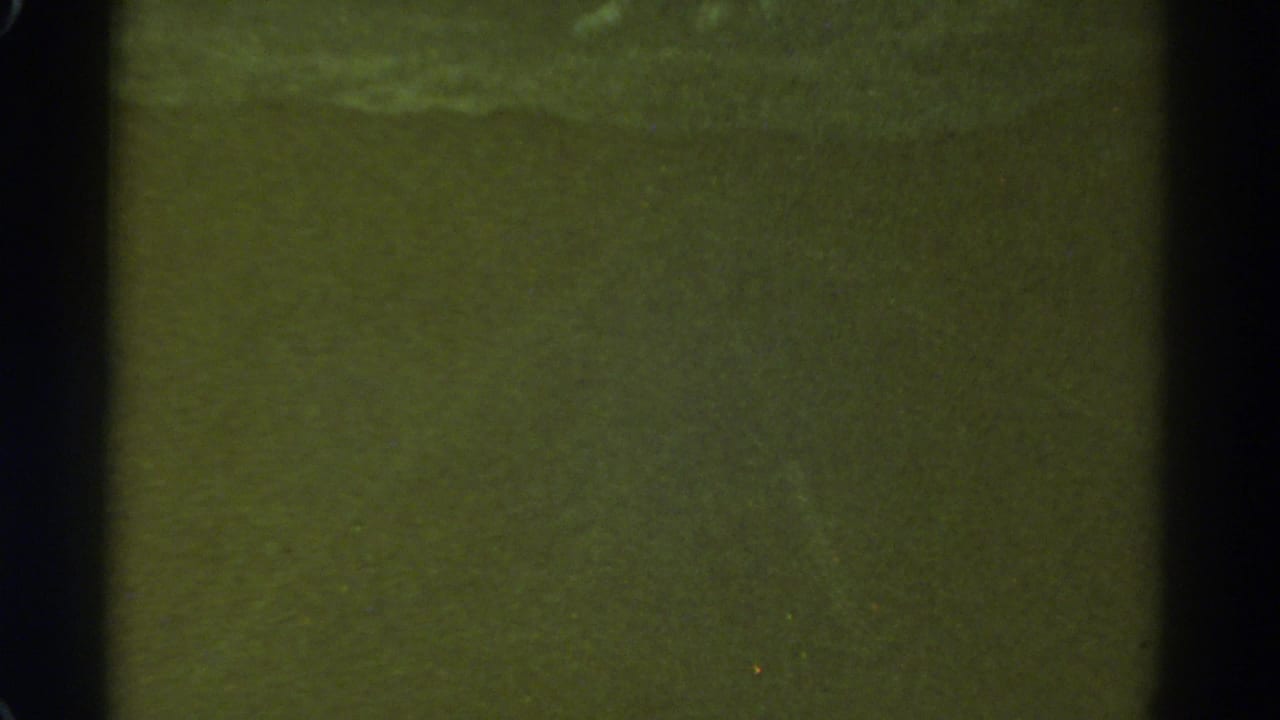 1967 Colorado 8mm night-driving frame with mostly dark green exposure, black gate edges, and scattered film specks.