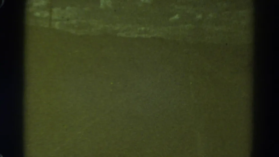 1967 Colorado 8mm frame with a faint horizontal light band across a dark night-driving view and visible film grain.