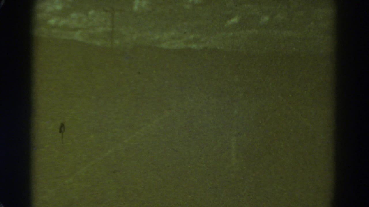 1967 Colorado 8mm frame showing a dim, indistinct road surface with film gate edges, grain and scratches.