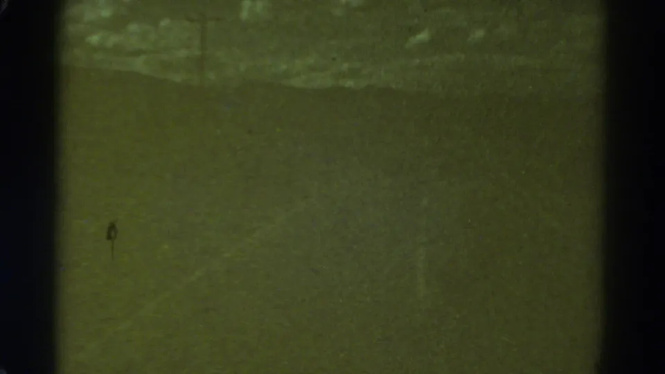 1967 Colorado 8mm frame showing a dim, indistinct road surface with film gate edges, grain and scratches.