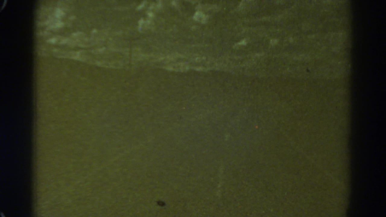 Low-light 1967 Colorado 8mm frame with a murky road area, soft focus and visible film border.