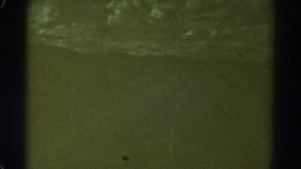 Low-light 1967 Colorado 8mm frame with a murky road area, soft focus and visible film border.