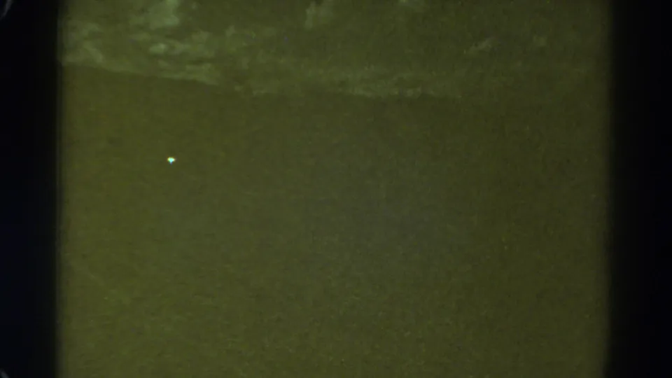 Low-light 1967 Colorado 8mm frame with a small bright point against a dark road-like surface.