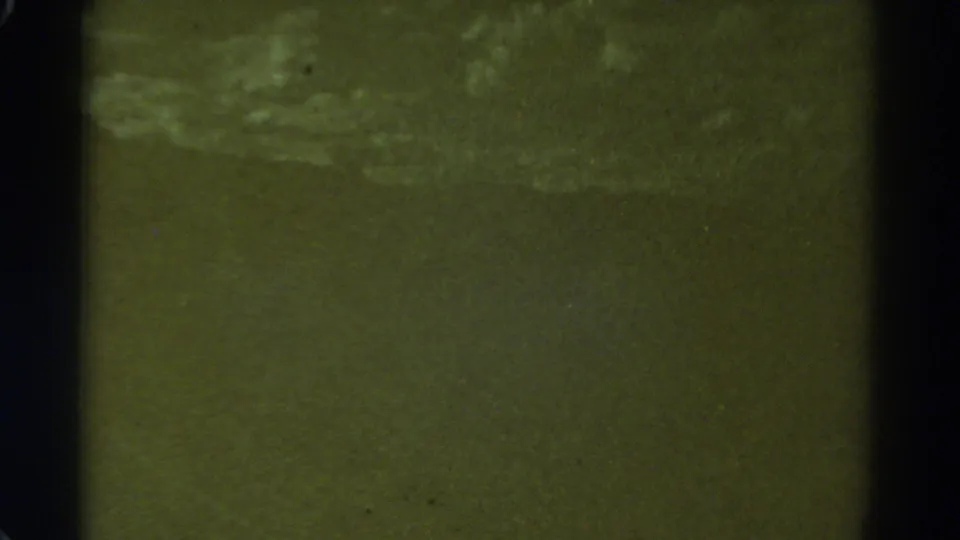 1967 8mm frame from supplied Colorado metadata showing an indistinct greenish shoreline or water surface with pale motion bands.