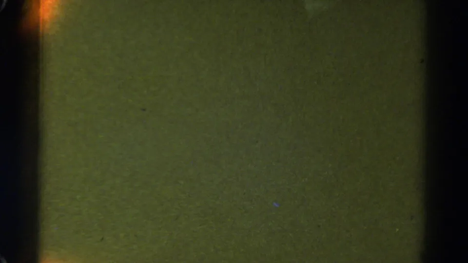 1967 Colorado 8mm frame showing a mostly dark, greenish road or night scene with faint orange glow along the left edge.
