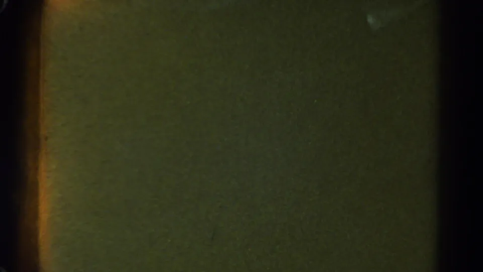 1967 Colorado 8mm frame showing a dim night scene with film-edge shadowing and a faint orange band near the left side.