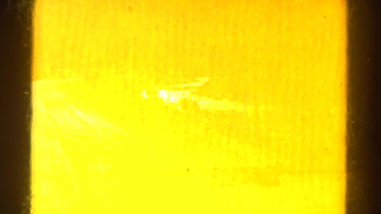 Overexposed amber film flare beside a dark vertical frame edge.
