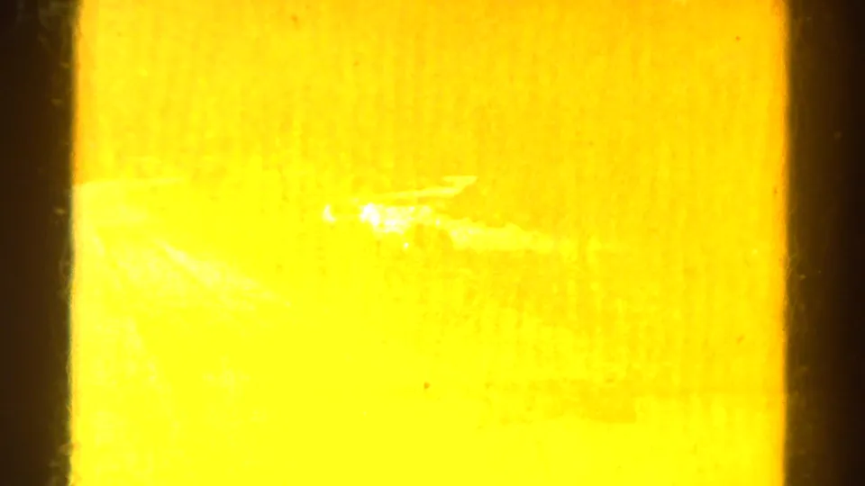 1967 Colorado 8mm frame opening on a bright amber exposure flare with dark film borders and little readable scenery.