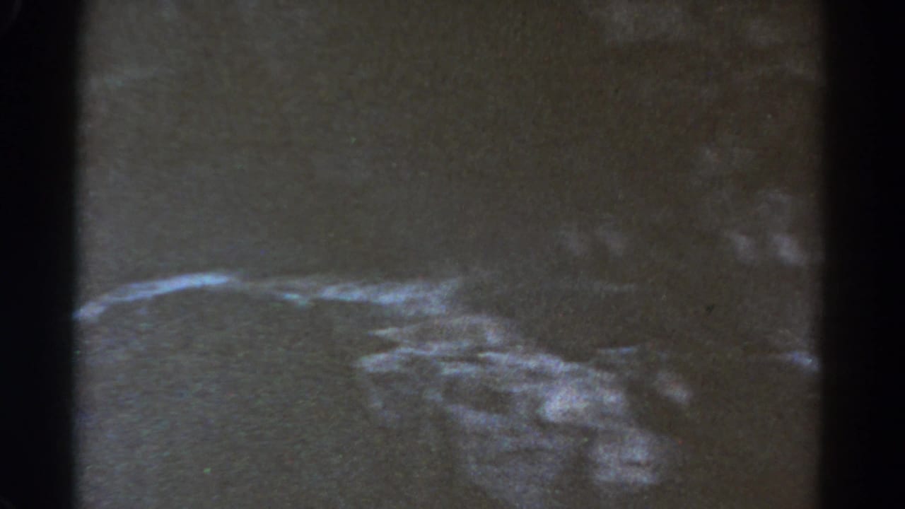 A shadowed, grainy view of rough terrain or hillside appears in the Colorado home-movie frame.