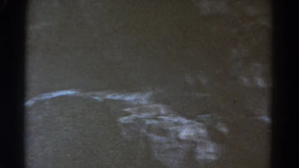 A shadowed, grainy view of rough terrain or hillside appears in the Colorado home-movie frame.
