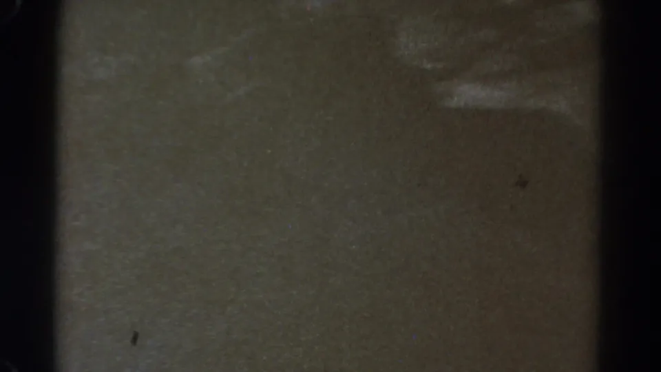 An underexposed 8mm frame shows faint bands of landscape or reflection with heavy grain and muted color.