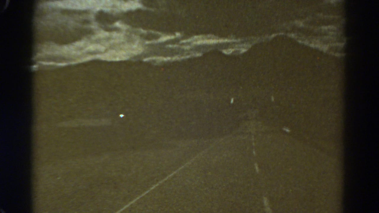 1967 Colorado 8mm frame showing a dim road receding toward a clouded horizon, with scratches and gate edges visible.