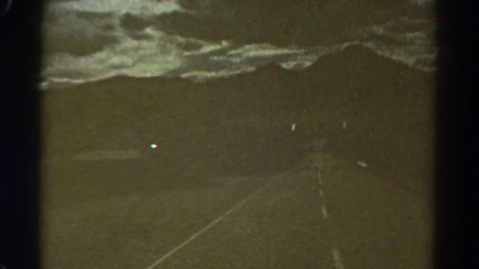 1967 Colorado 8mm frame showing a dim road receding toward a clouded horizon, with scratches and gate edges visible.