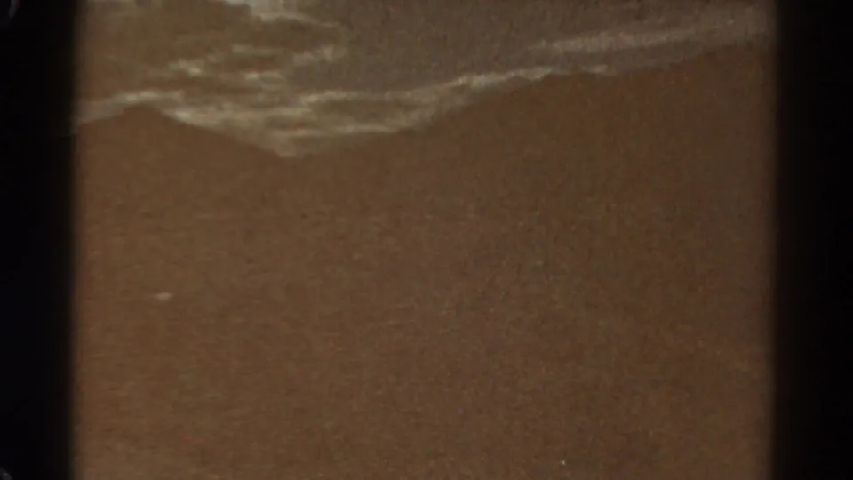 1967 Colorado 8mm frame showing an abstract brown outdoor surface with pale streaks, grain, and dark frame borders.