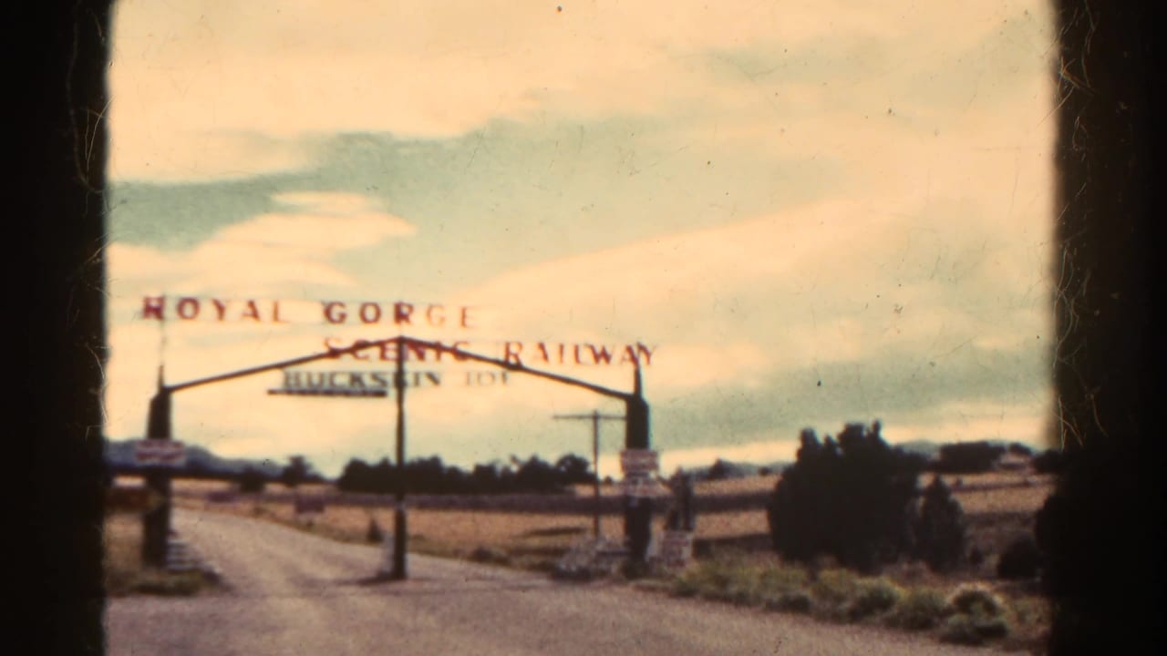 1967 Colorado 8mm frame showing the Royal Gorge Scenic Railway entrance sign and arch near an open roadside approach.