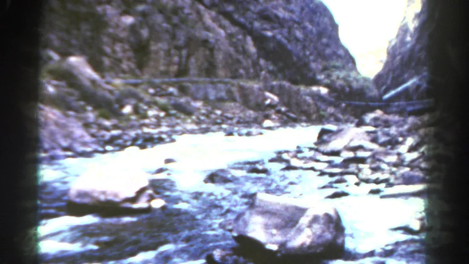 1967 Colorado 8mm frame showing a bright stream flowing between canyon walls and scattered boulders.