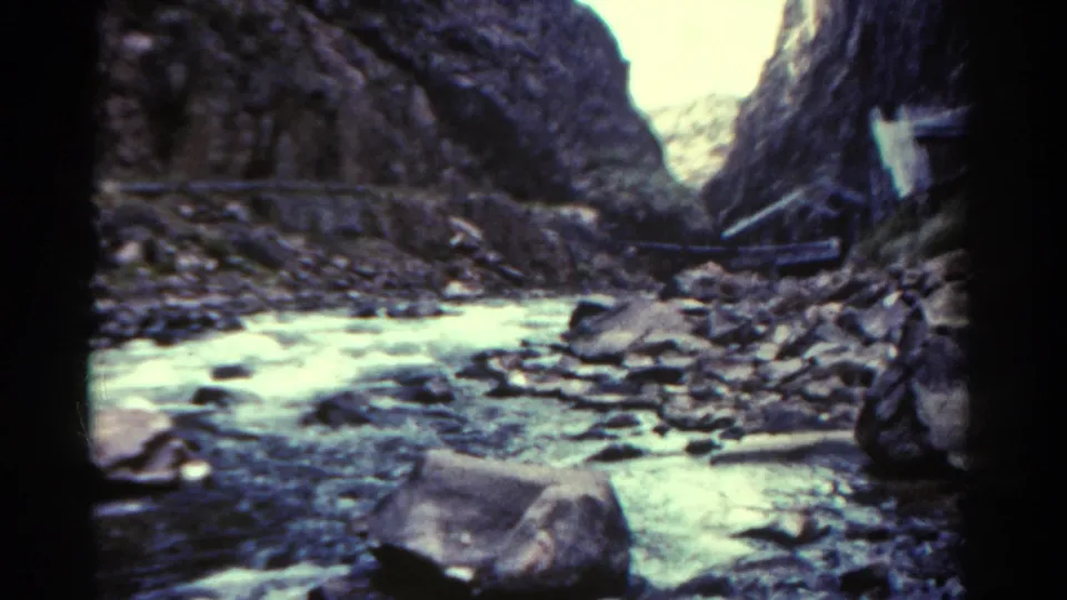 1967 Colorado 8mm frame showing pale water winding through a rocky canyon under dark cliff walls.
