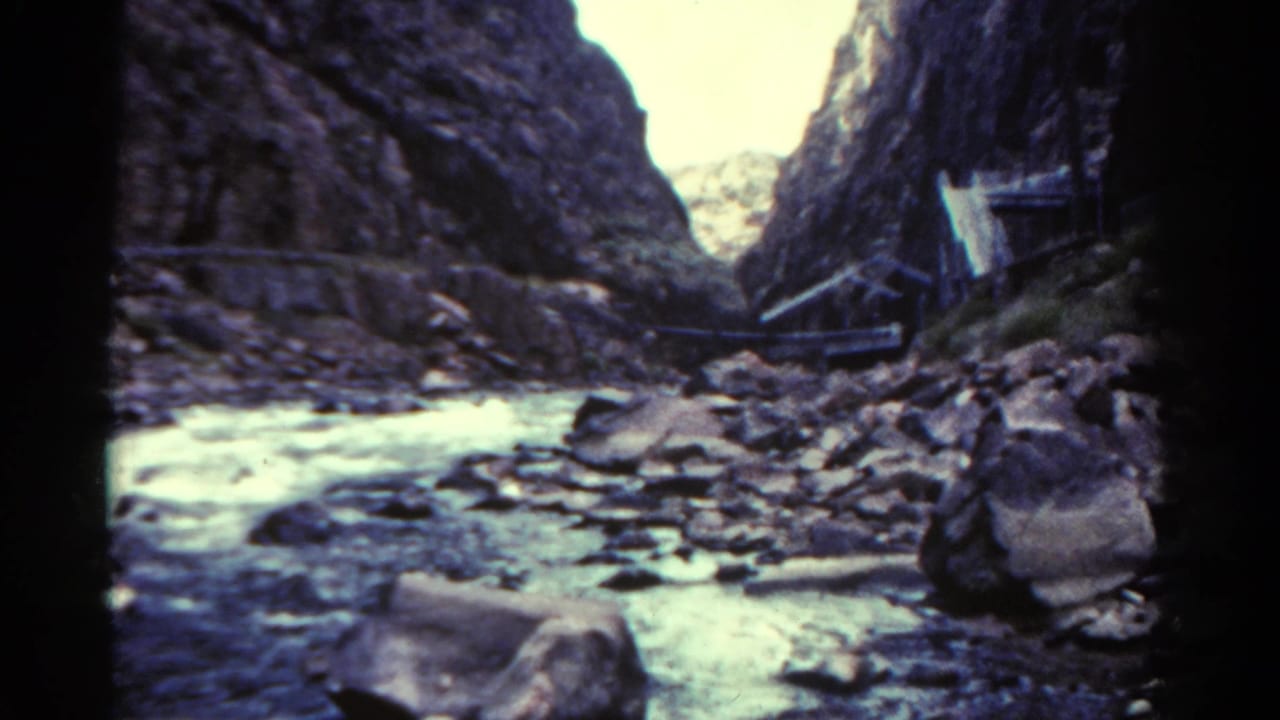 1967 Colorado home-movie view of water moving through a rocky canyon with steep dark walls.