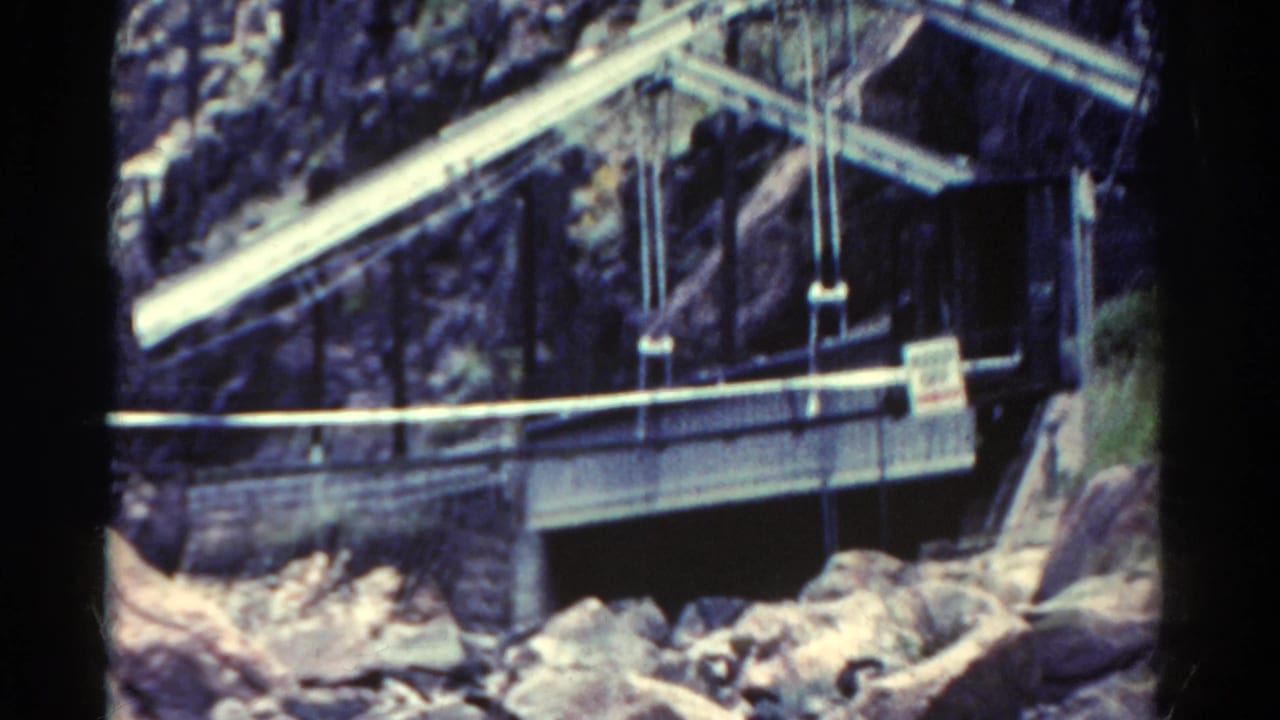1967 Colorado 8mm frame showing a metal bridge or industrial structure set against rugged canyon rock and boulders.