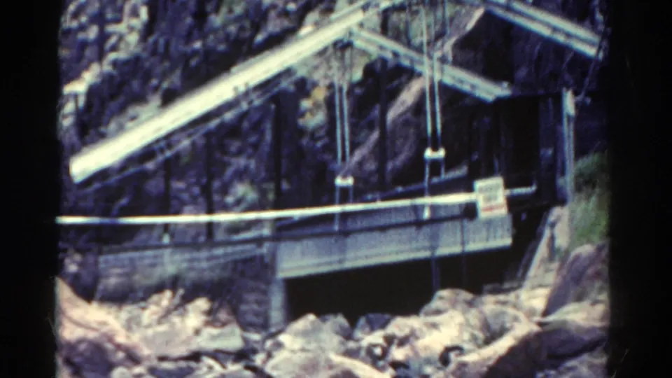 1967 Colorado 8mm frame showing a metal bridge or industrial structure set against rugged canyon rock and boulders.
