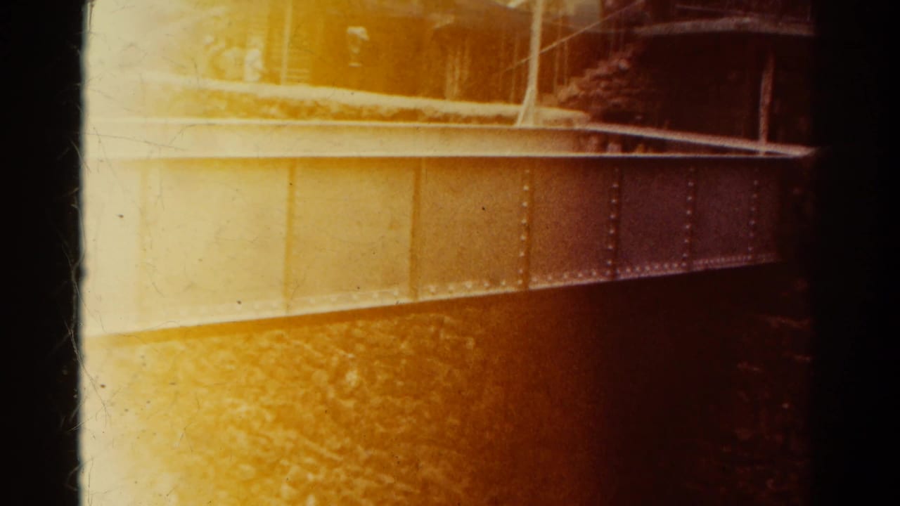 Warm 8mm frame of a metal railway structure beside a rocky canyon wall.
