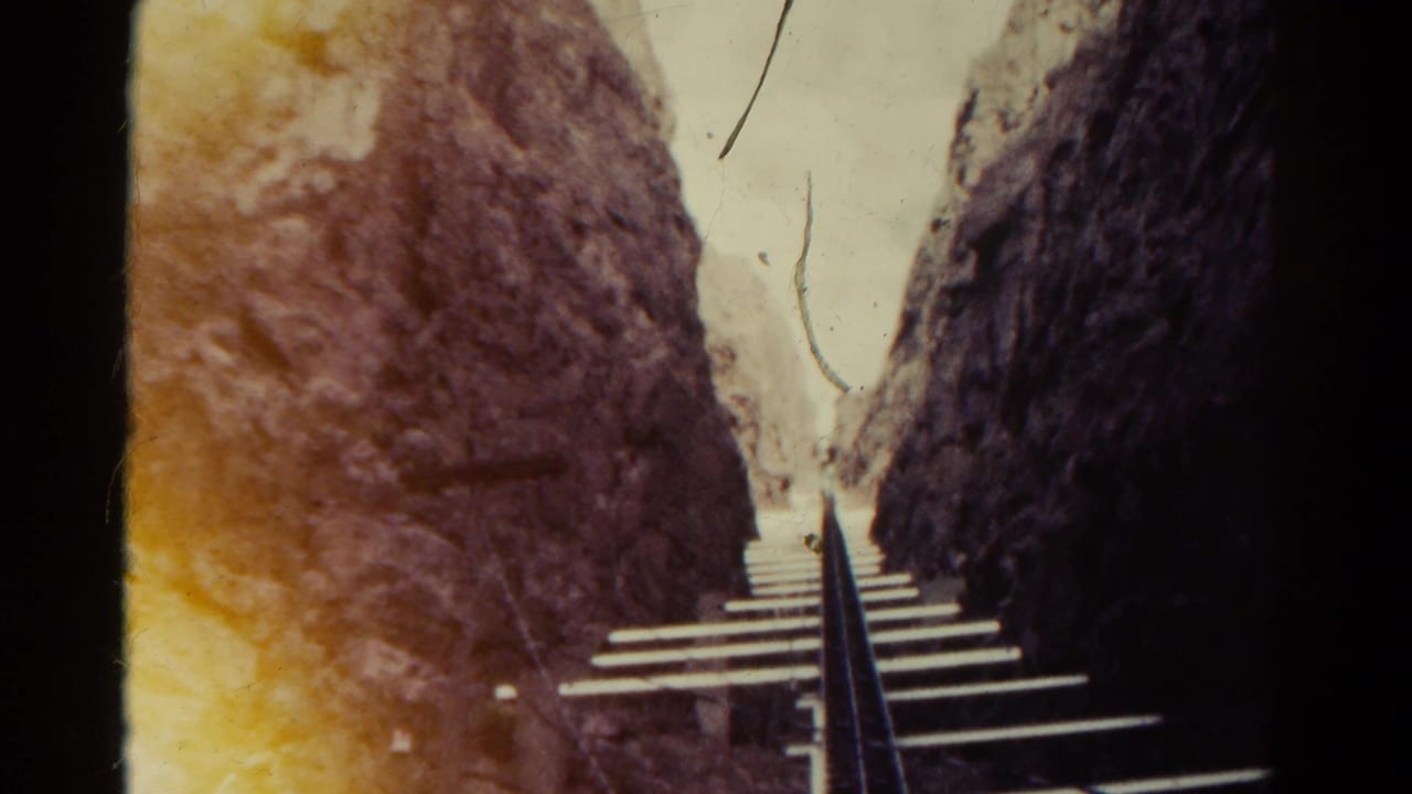 Steep narrow railway track rises between rocky canyon walls.