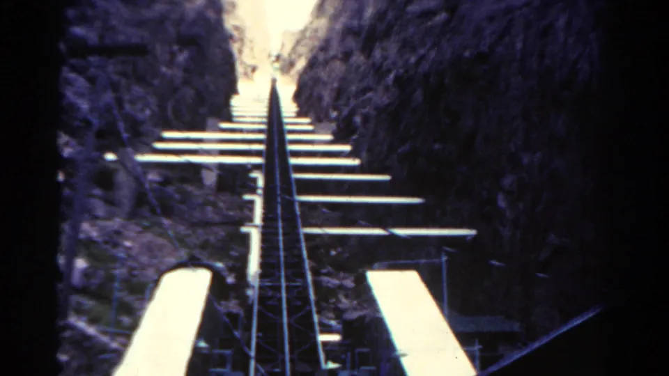 1967 Colorado 8mm frame looking along steep rails and pale track ties in a narrow rocky canyon.