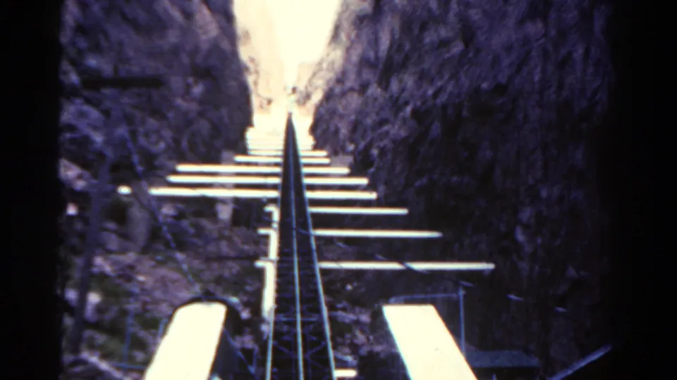 First-person 8mm view of a roller coaster climbing through a narrow rocky Colorado setting in 1967.