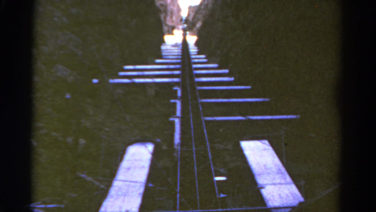 1967 Colorado 8mm frame showing metal rails and wooden ties climbing steeply between dark canyon walls.