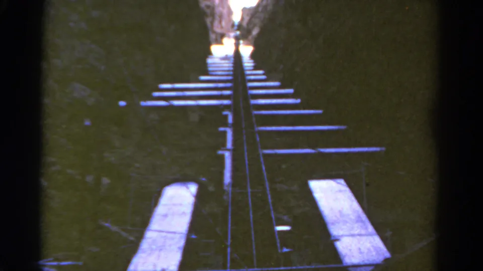 1967 Colorado 8mm frame showing metal rails and wooden ties climbing steeply between dark canyon walls.