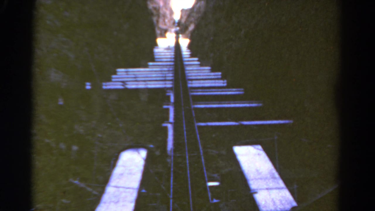 1967 Colorado 8mm frame of a narrow incline railway with wooden ties and side planks leading upward.