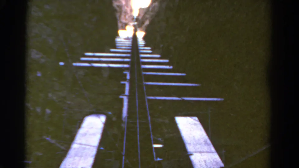 1967 Colorado 8mm frame looking up a steep rail structure with repeating wooden ties in a canyon setting.