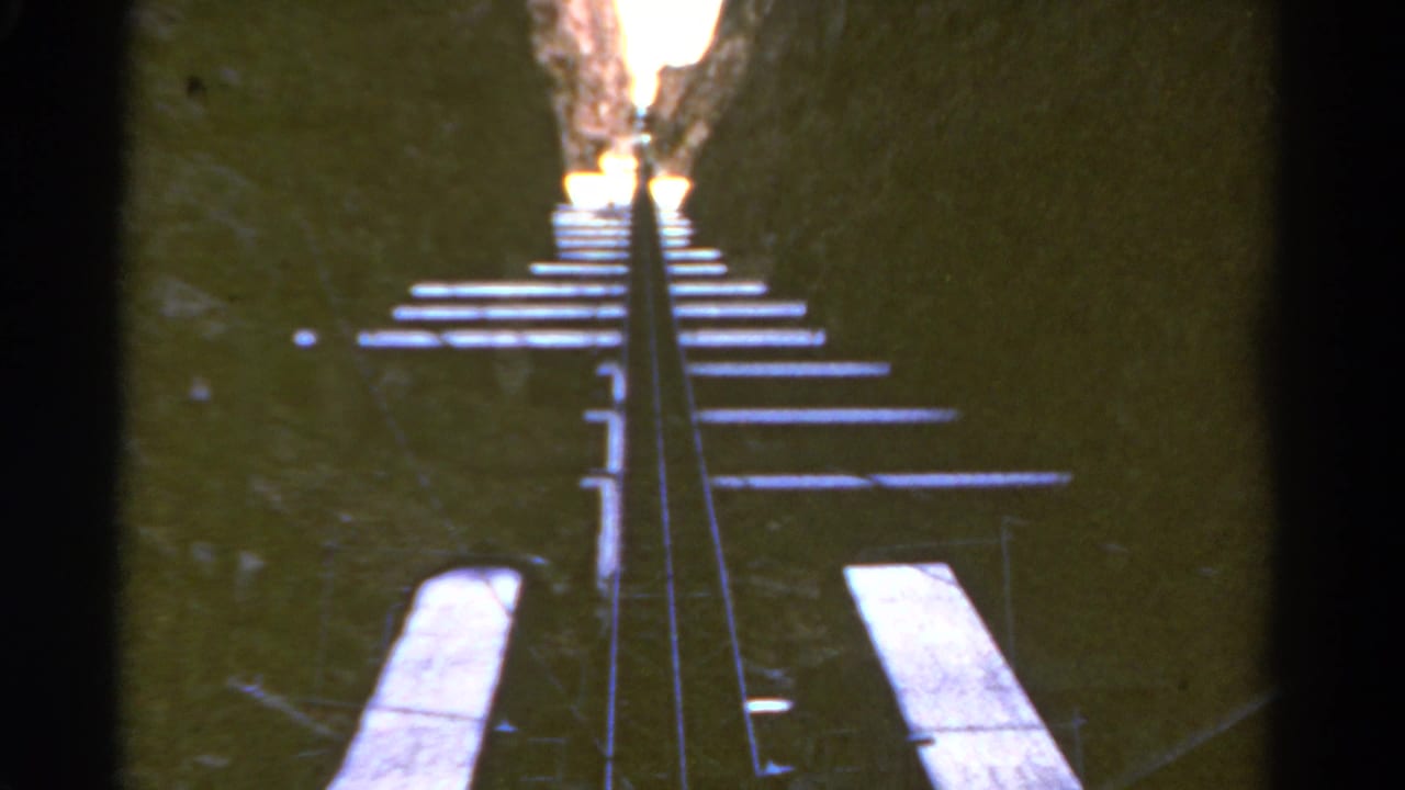 Upward view along rails and cross ties inside a rocky canyon.