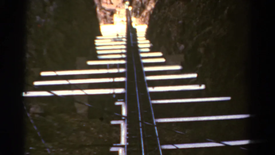1967 Colorado 8mm frame showing a steep narrow track, bright cross ties, and dark rock walls.