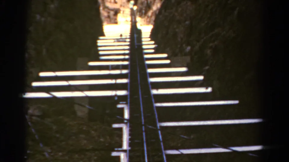 1967 Colorado 8mm frame looking up a narrow cavern stairway with white steps, dark rock sides, and central metal railings.