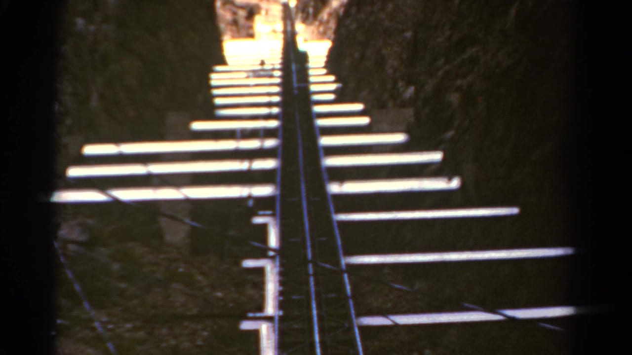 Narrow stairway and handrails lead upward through a shadowed rocky passage.